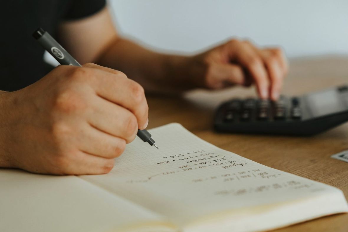 Notes z listą wydatków na wesele i kalkulator na stole